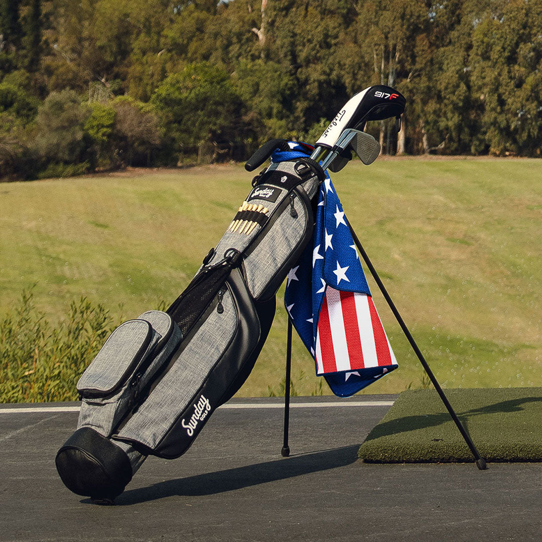 Gray Loma Bag by Sunday Golf golf bag with red white and blue towel at golf course