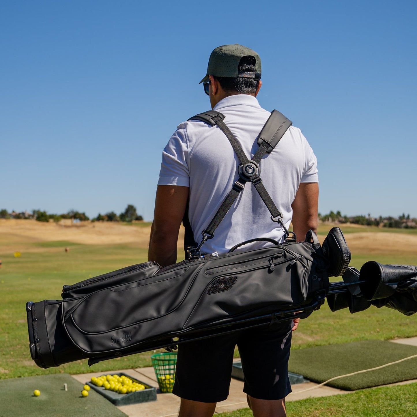 Black S-Class on course with a man showing off the bag and the double strap