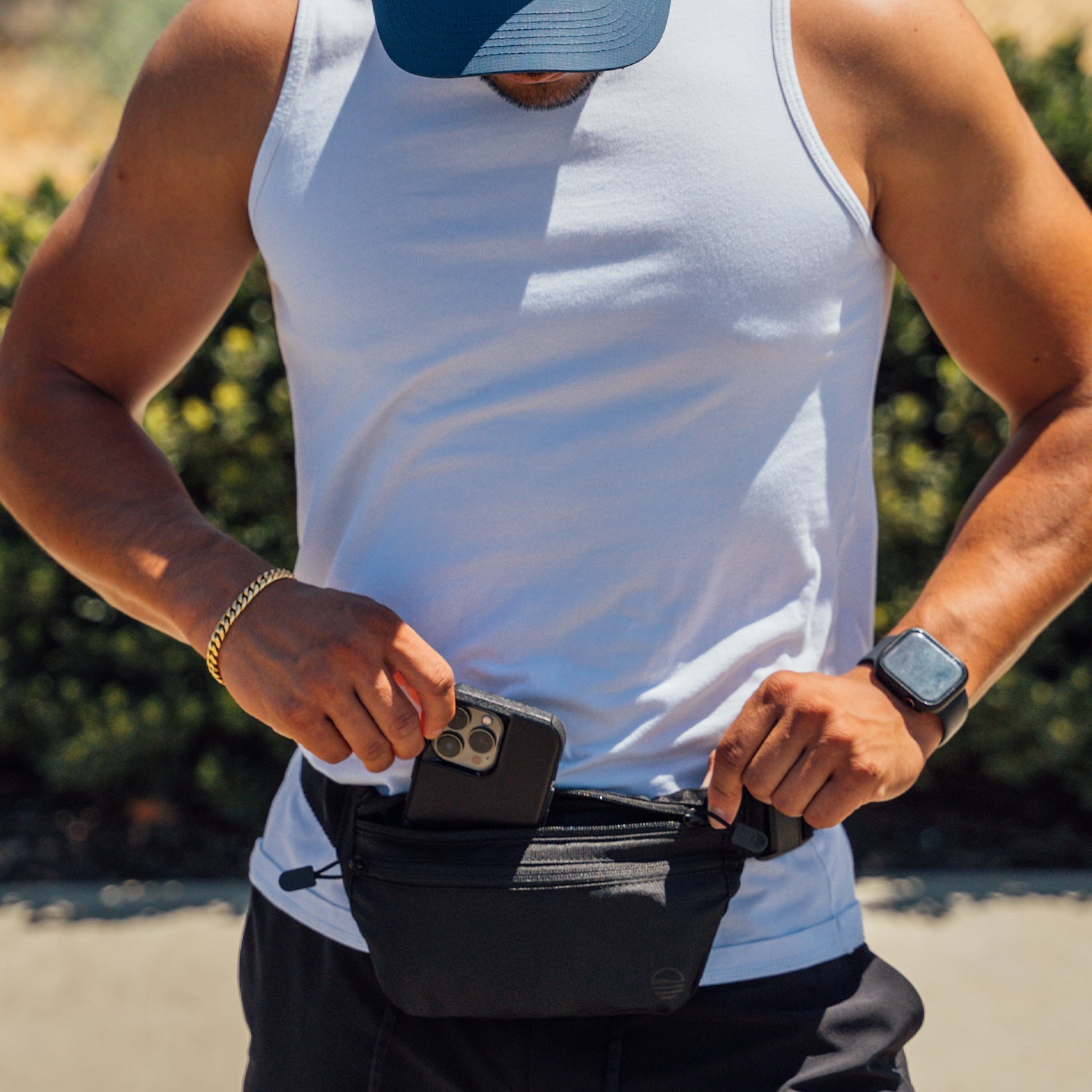 Black Runner Sling worn by a man as he places his iPhone inside.