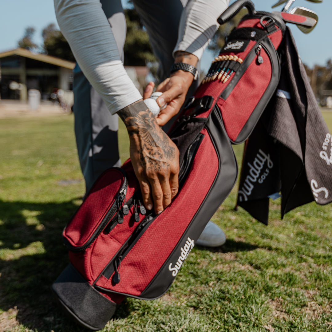 man putting golf balls into loma bag
