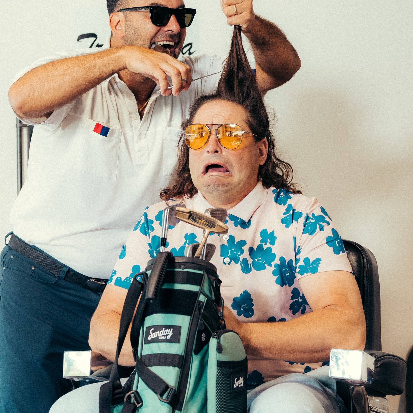 man holding seafoam loma xl golf bag while man cuts his hair