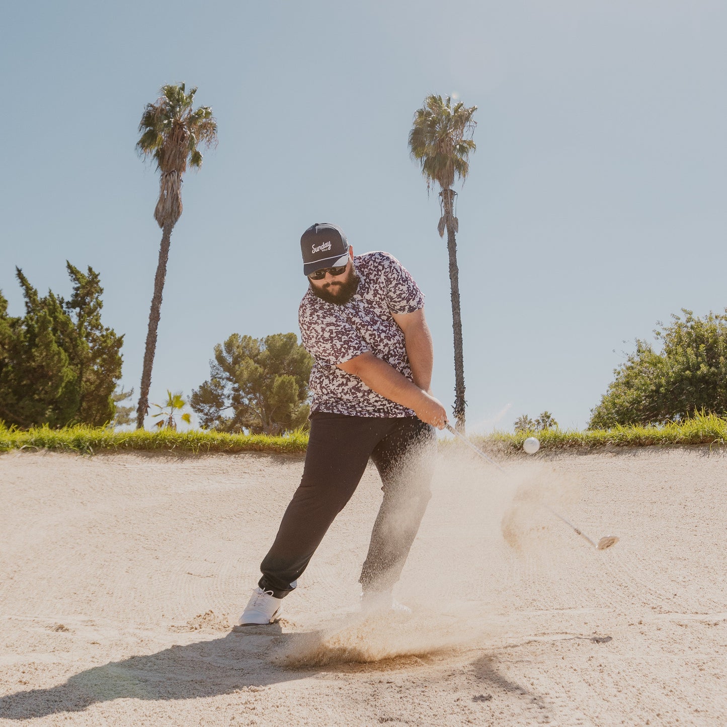 man in sand trap with navy rope hat