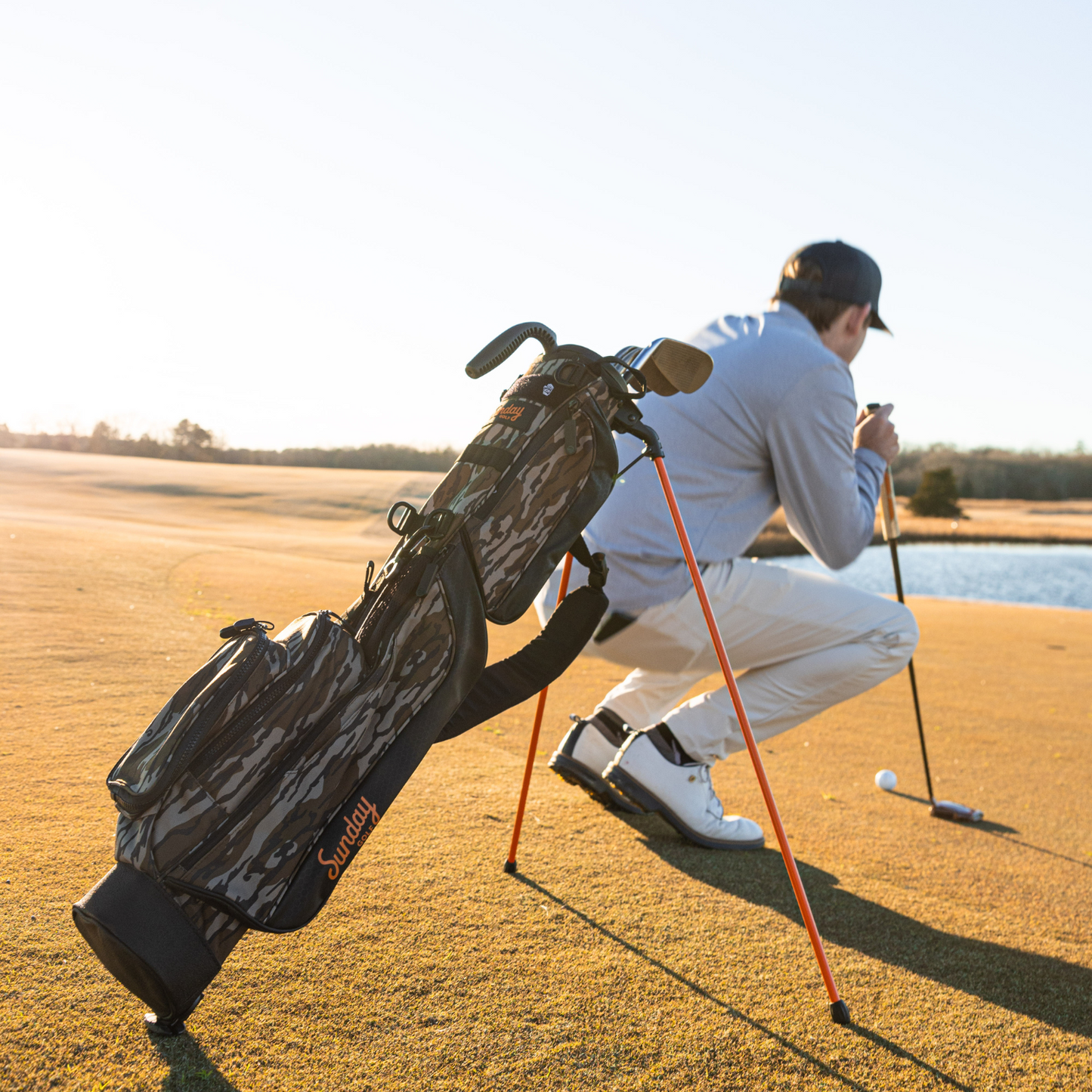 A man playing on the course with a mossy oak bottomland Loma golf bag behind him